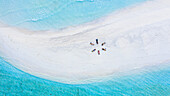 Aerial view of a group of women, doing sunrise yoga at a sandbank, Baa Atoll, Maldives.