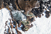 Luftaufnahme von zerklüfteten Felsen und krachenden Wellen entlang der dynamischen Küstenlinie, Terceira, Portugal.