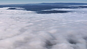 Aerial view of serene misty mountains and soft clouds under a dreamy sky, Eichenzell, Germany.
