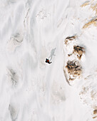 Aerial view of man standing on white sand Baltic sea beach near Klaipeda, Lithuania.