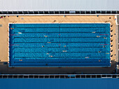Aerial view of people swimming in public pools surrounded by blue water and modern architecture, Westend, Berlin, Germany.