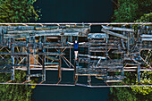 Aerial view of person lying down on old wooden collapsed bridge in Lithuanian countryside.