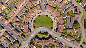 Aerial view of residential homes arranged in a circular pattern with green grass and roads, Exeter, England.