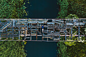 Aerial view of person lying down on old wooden collapsed bridge in Lithuanian countryside.
