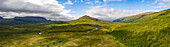 Luftaufnahme eines Flusses mit Panoramablick, der sich durch majestätische Berge und üppige Wälder unter einem bewölkten Himmel schlängelt, Abisko-Nationalpark, Norrland, Schweden