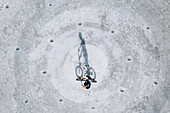Aerial view of BMX bike rider silhouette shadow standing on concrete surface in Panevezys, Lithuania.