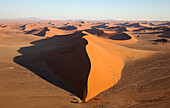 Luftaufnahme von Sanddünen in der Namib-Wüste. Die Kameldornbäume (Acacia erioloba) wachsen entlang des trockenen Flussbettes des Tsauchab-Flusses. Am Abend, Namib-Naukluft-Nationalpark, Namibia.