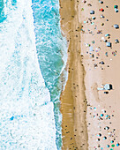 Aerial view of a busy beach full of people on the shoreline, view of Manhattan beach in Los Angeles, California, United States.