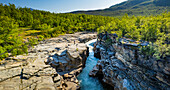 Luftaufnahme des wunderschönen Abiskojakka-Flusses, der durch eine majestätische Schlucht fließt, umgeben von ruhigen Wäldern und Felsen, Abisko-Nationalpark, Schweden.