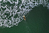 Aerial view of surfer paddling out on surf board in Baltic sea near Klaipeda, Lithuania.