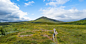 Luftaufnahme von ruhigen Bergen und einem gewundenen Fluss mit Wanderern auf einem Pfad, Abisko Nationalpark, Schweden.