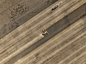Aerial view of cereal harvesters and tractors at a farm in Brandenburg, Germany.