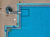 Aerial view of a clean and geometric public pool with blue tiles on a sunny day, Oberschoneweide, Berlin, Germany.
