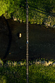 Aerial view of person lying down on rope bridge going over the river, Birstonas, Lithuania. Shot during sunset in Spring time.