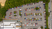 Aerial view of a bustling carpark with parked vehicles and a supermarket surrounded by greenery, Bude, United Kingdom.
