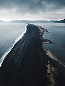 Luftaufnahme eines schwarzen Sandstrandes, der sich entlang der Küste im Naturschutzgebiet Hvalnes, Austurland, Island, erstreckt.
