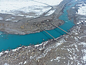 Aerial view of snowy mountains, river, and bridge in remote Skardu, Punjab, Pakistan.