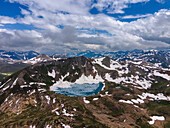Aerial view of majestic snowy mountains and a pristine icy lake under dramatic clouds, Sambaksar Pass, Gilgit Baltistan, Pakistan.