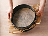 Backpapier auf den Springformboden legen und mit dem Rand der Form einspannen