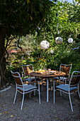 Terrace dining area with wooden table and lanterns under trees