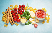 Italian ingredients - tomato sauce, grissini, pasta, basil, parmesan and olive oil