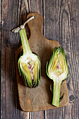 Halved artichoke on wooden cutting board