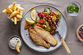 Fried fish fillet with potato side dish and tomato salad