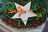 Holzstern mit Beerenzweig im Adventsgesteck aus Tannenzweigen