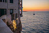 Sailing boat and Polignano a Mare skyline at sunset, Puglia, Italy