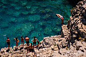People swimming and jumping into the sea from Pendma Chiatt (Pietra Piatta), Polignano a Mare, Puglia, Italy
