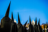 Nazarenes wearing black hoods participate in a solemn procession during Holy Week in Seville, Andalusia, capturing the spirit of tradition.