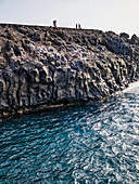 Visitors enjoy breathtaking views at the Los Hervideros cliffs in Lanzarote, looking out over the crashing waves of the Atlantic Ocean.
