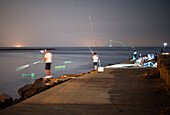 Anglers set up on the Isla Canela breakwater at Punta del Moral, fishing at night while the starry sky twinkles above.