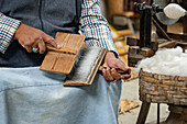 A master weaver cards wool for spinning in the Tahuantinsuyo Weaving Workshop, Otavalo, Ecuador.