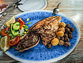 Enjoy a delicious grilled horse mackerel jurel garnished with fresh salad and traditional papas arrugas on a beautiful day in Lanzarote.
