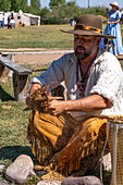 A man in period dress crushes tinder for starting a fire with flint and steel at the Fort Bridger Mountain Man Rendezvous in Wyoming.