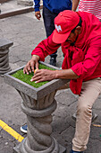 A man trying to balance an egg on its end at the equator in Mitad del Mundo, Ecuador.