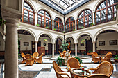Visitors relax in the elegant courtyard of the 18th-century Marqués de la Gomera hotel in Osuna, Seville, enjoying the unique architecture.