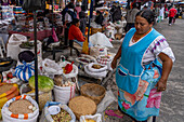 A Quechua Amerindian woman in traditional dress sells foodstuffs in the open market in Quito, Ecuador.