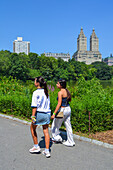 Young girls visiting Central Park Lake with Upper West Side's prominent buildings in the background, New York City, USA