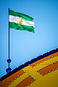 The flag of Andalusia proudly waves above the entrance gate of the vibrant April Fair in Seville, showcasing regional pride and celebration.