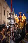 Seville, Spain, March 27 2018, During Holy Week in Seville, the procession features silver candlesticks held by participants, with a paso blurred in the background.