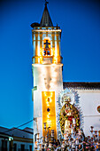 Our Lady of the Rosary statue is displayed on a float during a nighttime procession in Carrión de los Céspedes, Seville, Andalusia.