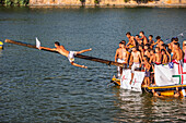 Seville, Spain, July 24 2012, In Seville's Triana neighborhood, a young man stretches for the flag while teammates cheer him on during the festive cucaña event.