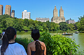 Young girls visiting Central Park Lake with Upper West Side's prominent buildings in the background, New York City, USA