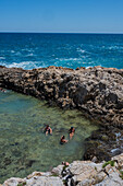 People enjoying a summer day in the natural pool of Grottone, Polignano a Mare, Puglia, Italy