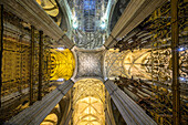 Inside Seville Cathedral, ribbed vaults rise above clustered pillars, illuminated by light filtering through the lantern's height.