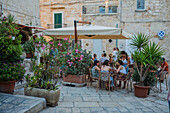 People enjoying lunch in a restaurant terrace surrounded by plants, Polignano a Mare, Italy
