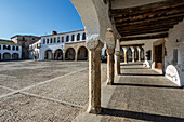 Visitors enjoy the historic arcades and sunny architecture of Plaza Mayor in Garrovillas de Alconetar, Extremadura.