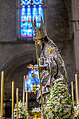 The colorful statue of Saint Leander, decorated with flowers and candles, joins Seville's Corpus Christi procession in faith.